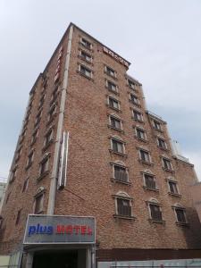 a tall brick building with a sign in front of it at Plus Motel in Busan