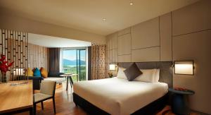 a hotel room with a large bed and a desk at PARKROYAL Penang Resort in Batu Ferringhi