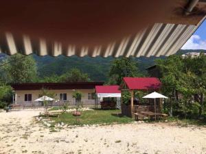 un edificio con mesas y sombrillas delante en Guest House Shavnabada en Ambrolauri