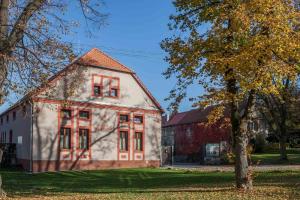 an old white house with red windows and a tree at Agropenzion U Bartousku in Malíkovice