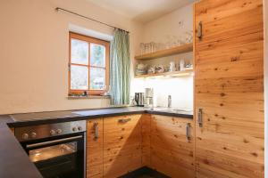 uma cozinha com armários de madeira e um forno de fogão preto em Das Prinzis em Lofer
