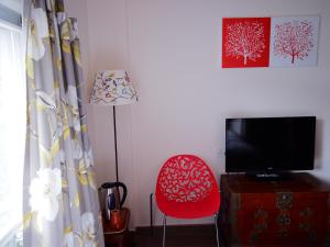 a room with a red chair and a flat screen tv at Tai O Inn, by the Sea in Hong Kong