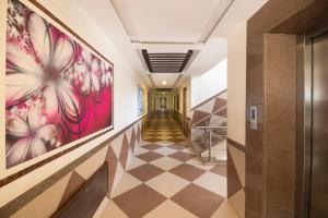 a hallway with a checkered floor and art on the walls at Hotel Vaikunth By Adamo in Nāthdwāra
