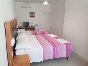 1 dormitorio con 2 camas y TV. en Duna camere con bagno, en Lido Adriano