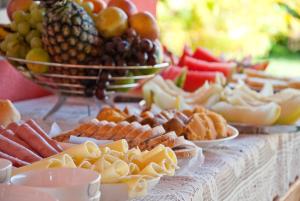 un buffet de queso y otros alimentos en una mesa en La Dolce Vita Flat & Pousada en Praia do Frances