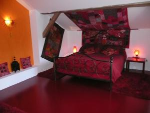 1 dormitorio con cama roja y dosel en Au Palton, en Raon-aux-Bois