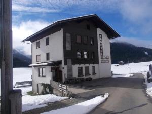 a building in the snow next to a road at Pension Anderlehof in Sankt Lorenzen im Lesachtal