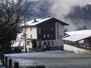 un edificio con nieve en el suelo junto a una casa en Pension Anderlehof en Sankt Lorenzen im Lesachtal