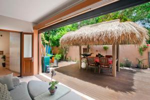 un patio con una mesa y una sombrilla de paja en L'Auberge Noosa en Noosa Heads