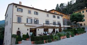 a building with people sitting under an umbrella outside at La Locanda Di Cetona in Cetona