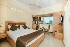 a bedroom with a large bed and a desk at Yogi Broadway in Mumbai