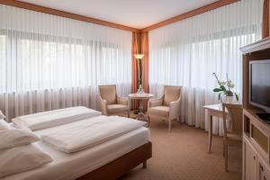 a hotel room with a bed and chairs and a television at Hollywood Media Hotel am Kurfürstendamm in Berlin