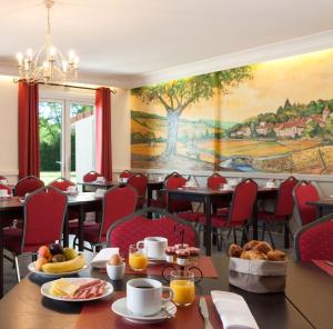 un restaurant avec des tables et des chaises et une peinture murale. dans l'établissement Hôtel Carline Beaune, à Beaune