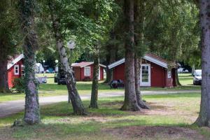 a group of trees in front of a red cabin at Nordskoven Strand Camping in Rønne