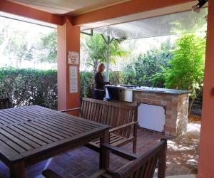 a man standing behind a barbecue grill on a patio at Sylvan Beach Resort in Bellara