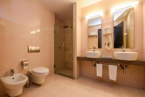 ein Badezimmer mit zwei Waschbecken, einem WC und einer Dusche in der Unterkunft Sky Hotel Tirana in Tirana