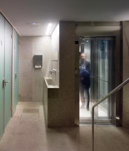 サンティアゴ・デ・コンポステーラにあるホテル パソ デ アルタミラの建物内の浴室に入る男