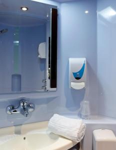 La salle de bains bleue est pourvue d'un lavabo et d'un miroir. dans l'établissement A&H PRIVILÈGE Lyon Est - Saint Priest Eurexpo, à Saint-Priest