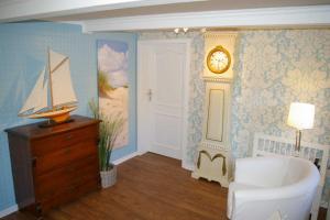 Risum-LindholmにあるFerienhaus Klookris 15の壁に時計と白い椅子が備わる客室です。