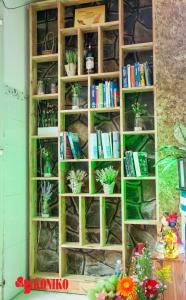 a book shelf filled with books and potted plants at Koniko Hotel in Ho Chi Minh City
