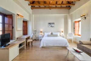ein Schlafzimmer mit einem Bett, einem Fernseher und einer Couch in der Unterkunft Mare Monte Luxury Suites in Spetses