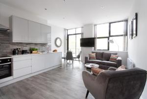 a kitchen and living room with a couch and a table at Cotels at 7Zero1 Serviced Apartments - Modern Apartments, Superfast Broadband, Free Parking, Centrally Located in Milton Keynes