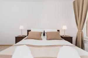 a bedroom with a large white bed with two lamps at Grace Apartment II in Kołobrzeg +48 photos