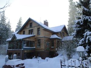 a large wooden house with snow on it at Hotel Magnes in Szklarska Poręba