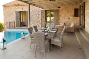 a patio with a table and chairs and a pool at Euphoria Retreat in Mánganos