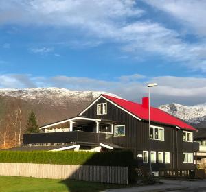 a black house with a red roof with mountains in the background at Villa Åndalsnes in Åndalsnes
