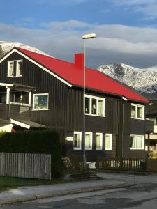dom z czerwonym dachem z górami w tle w obiekcie Villa Åndalsnes w Åndalsnes