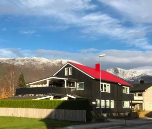 オンダルスネスにあるVilla Åndalsnesの山を背景に赤い屋根の黒い家