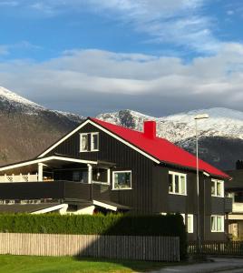 une maison noire avec un toit rouge et des montagnes en arrière-plan dans l'établissement Villa Åndalsnes, à Åndalsnes