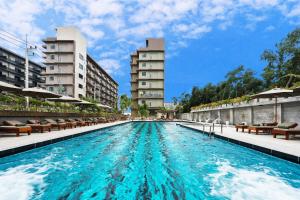 a large swimming pool with two tall buildings at Olive Tree Hotel in Na Jomtien