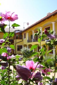 ein gelbes Gebäude mit rosa Blumen davor in der Unterkunft Weingut - Gästezimmer zum Schwalbennest in Herrnbaumgarten