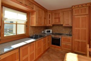 una cucina con armadi in legno, lavandino e finestra di Casa Alu' a Bormio