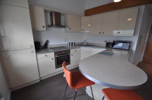 a kitchen with white cabinets and a table and orange chairs at Princes Dock Chambers 10 in Hull