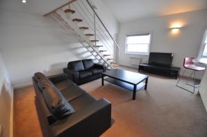a living room with a couch and a table and a staircase at Princes Dock Chambers 10 in Hull
