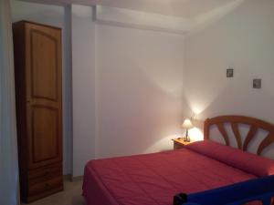 a bedroom with a red bed and a wooden door at Apartamentos Aixa in Caravaca de la Cruz