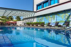 een zwembad voor een gebouw met stoelen bij Novotel Sao Paulo Center Norte in Sao Paulo