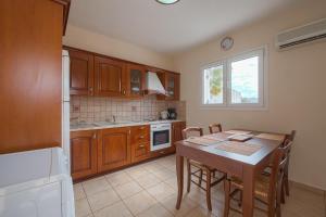 a kitchen with a wooden table and a dining room at Athena Villa in Kolimbia