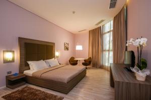 a hotel room with a bed and a desk and window at Sky Hotel Tirana in Tirana