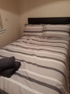 a bed with a black and white striped blanket at Handy Dale House in Bathgate
