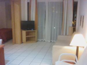 ein Wohnzimmer mit einem TV und einem weißen Boden in der Unterkunft Beach Class Muro Alto - flat in Porto De Galinhas