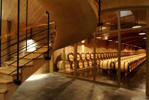 a wine cellar with a staircase and a bunch of wine barrels at Château du Tertre in Arsac