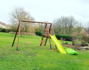 a playground with two swings and a slide at La Grange, gîte classé, 300m du canal & vélo-route, 2km du centre de Dole in Dole