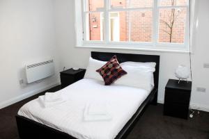 a bedroom with a bed with white sheets and a window at Princes Dock Chambers 2 in Hull