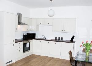 a white kitchen with white cabinets and a table at Princes Dock Chambers 2 in Hull