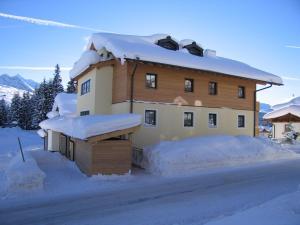 a house covered in snow with a pile of snow at Fewo Simone in Königsleiten