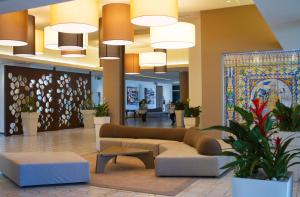 a lobby with a couch and tables and potted plants at MClub Lipari in Sciacca